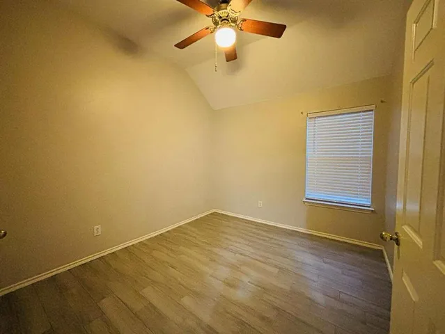 a view of an empty room with window and wooden floor