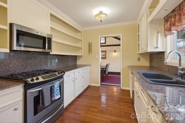a kitchen with stainless steel appliances granite countertop a stove a sink and a microwave