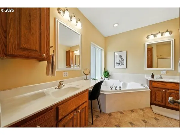a spacious bathroom with a tub sink and mirror