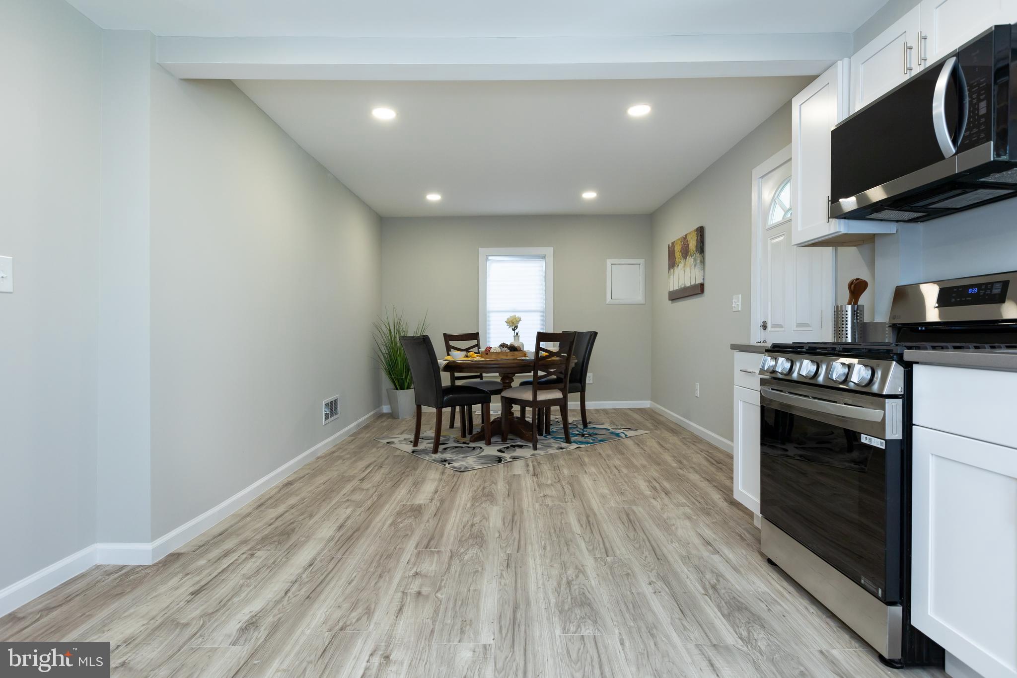2407 Hammonds Ferry Road Halethorpe, MD 21227 - Photo 9 of 43 a kitchen with stainless steel appliances granite countertop a stove top oven a sink dishwasher a dining table and chairs with wooden floor
