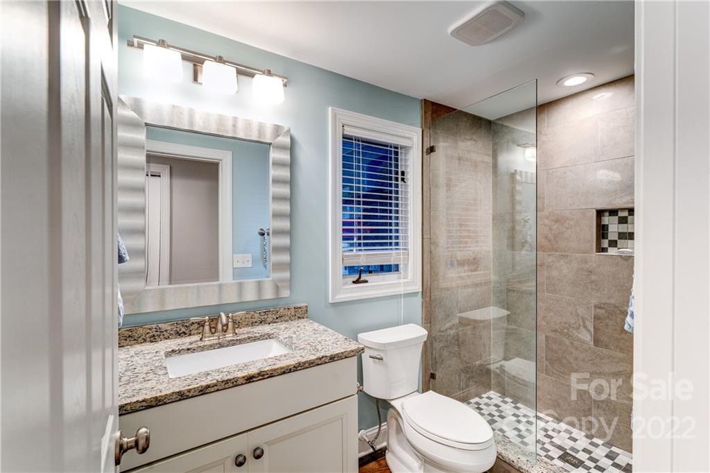 4027 Windward Drive Tega Cay, SC 29708 - Photo 38 of 44 a bathroom with a granite countertop sink toilet a mirror and shower