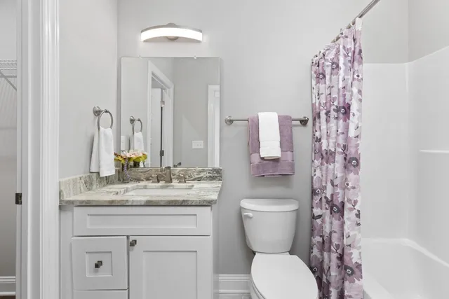 a bathroom with a granite countertop toilet sink and mirror