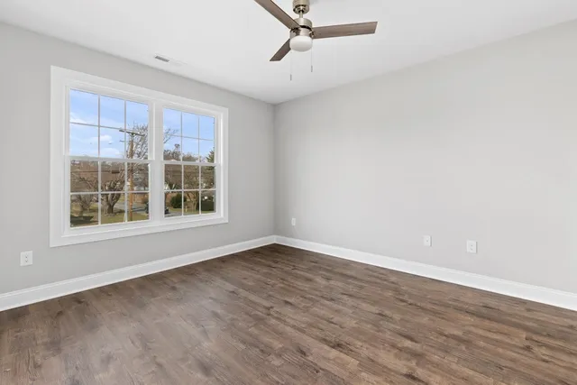 an empty room with wooden floor and windows