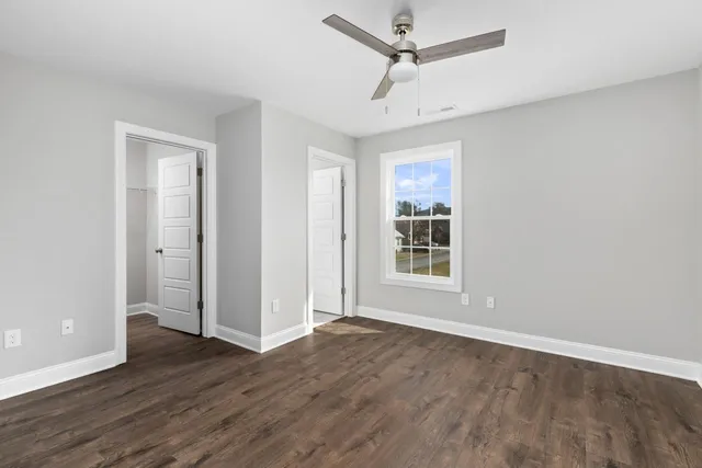 a view of empty room with wooden floor and fan