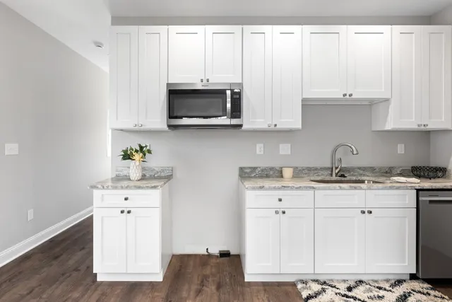 a kitchen with stainless steel appliances granite countertop a sink a stove and a microwave with wooden floor