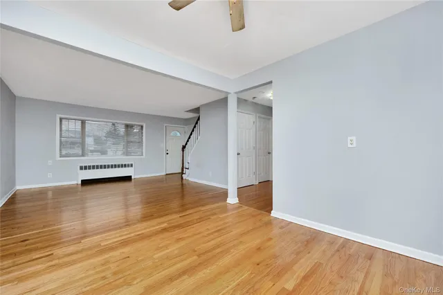 an empty room with wooden floor ceiling fan and windows