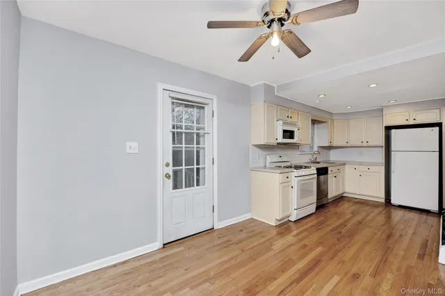 a kitchen with granite countertop a refrigerator a stove a sink dishwasher a dining table and chairs with wooden floor