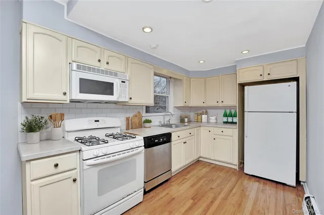a kitchen with white cabinets white stainless steel appliances and wooden floors