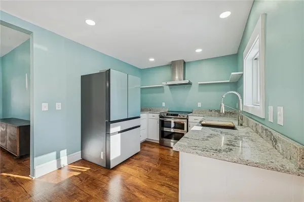 a kitchen with stainless steel appliances granite countertop a refrigerator a stove and a sink