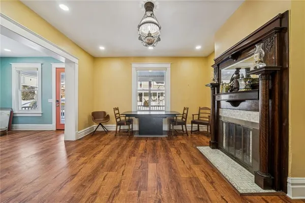 a view of a livingroom with furniture a fireplace wooden floor and windows