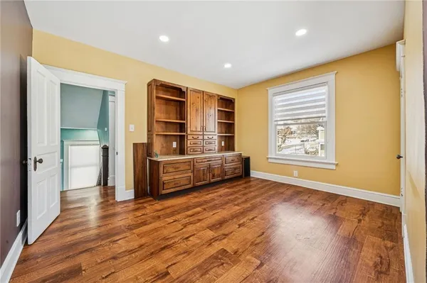 a view of an empty room with wooden floor and windows