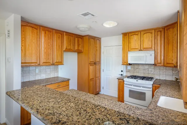 a kitchen with stainless steel appliances granite countertop a sink stove and cabinets