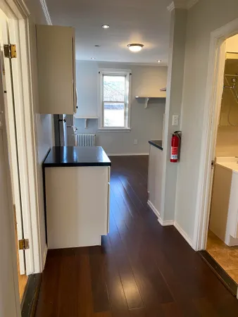 a kitchen with a refrigerator and wooden floor
