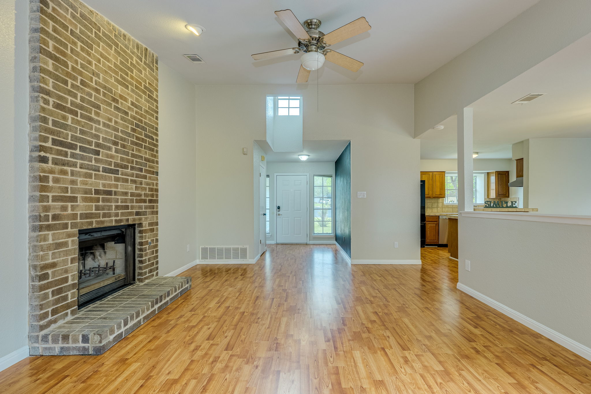 4815 Transit Circle Austin, TX 78727 - Photo 4 of 35 Spacious living area featuring a dramatic floor-to-ceiling brick fireplace with a raised hearth, wood-look flooring, and a tall vaulted ceiling that enhances the open, airy feel.