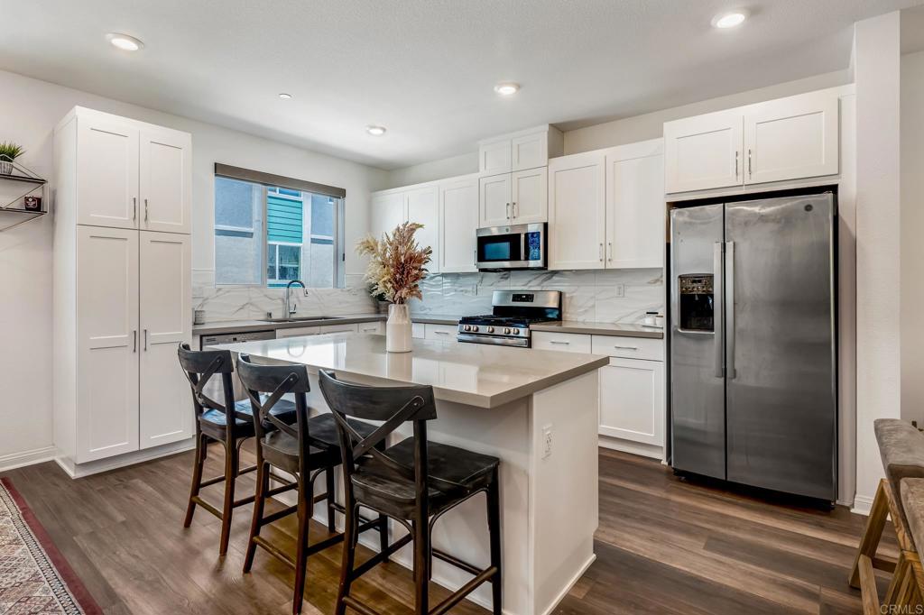 1978 Affinity Lane Chula Vista, CA 91915 - Photo 6 of 26 a kitchen with stainless steel appliances a refrigerator a stove a sink and white cabinets with wooden floor