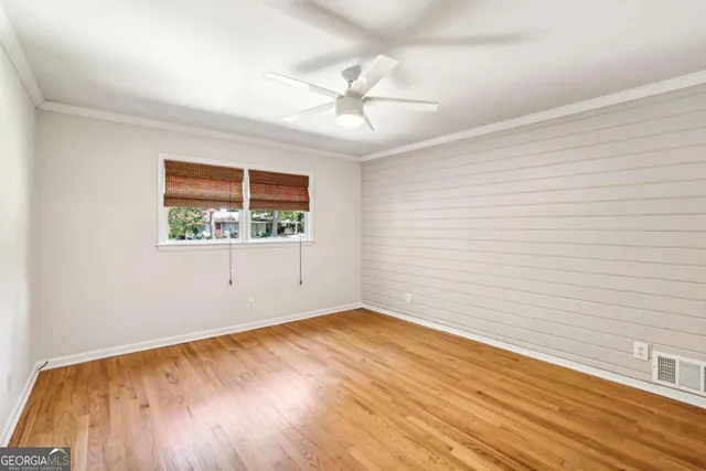 an empty room with wooden floor chandelier fan and windows