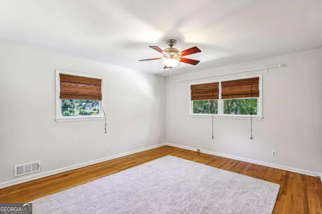 a view of an empty room with a window and wooden floor