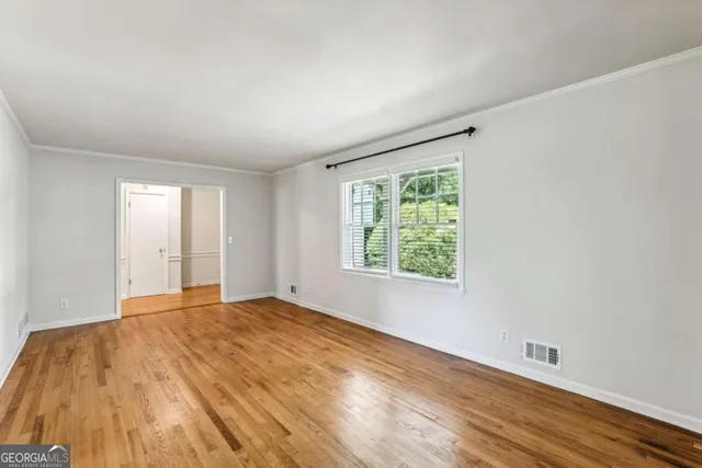 a view of an empty room with wooden floor and a window