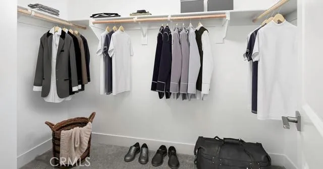a view of walk in closet with clothes and shoes