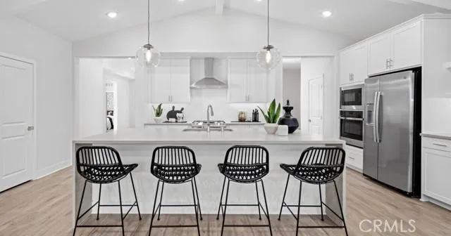 a kitchen with stainless steel appliances a table chairs refrigerator and wooden floor