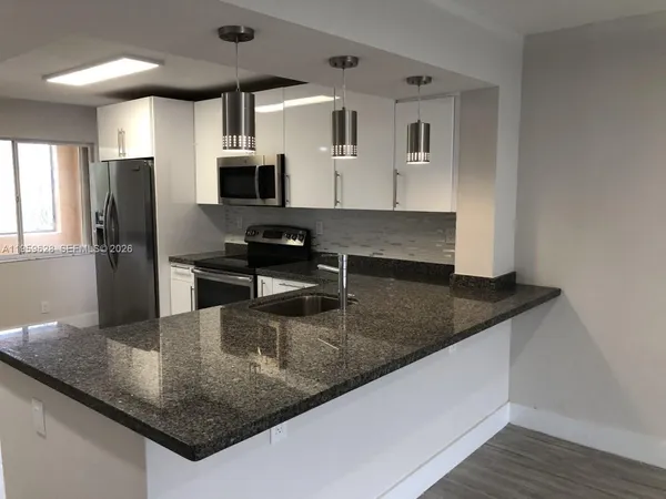 a kitchen with granite countertop a sink a counter top space appliances and cabinets