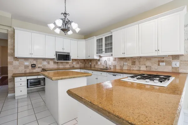 a kitchen with kitchen island granite countertop stainless steel appliances a stove a sink a counter top space and cabinets
