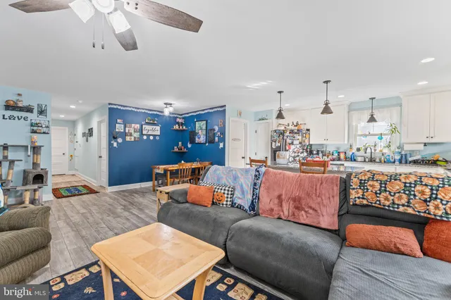 a living room with furniture kitchen view and a wooden floor