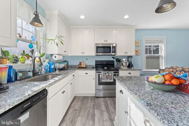 a kitchen with stainless steel appliances granite countertop a sink a stove and a wooden floors