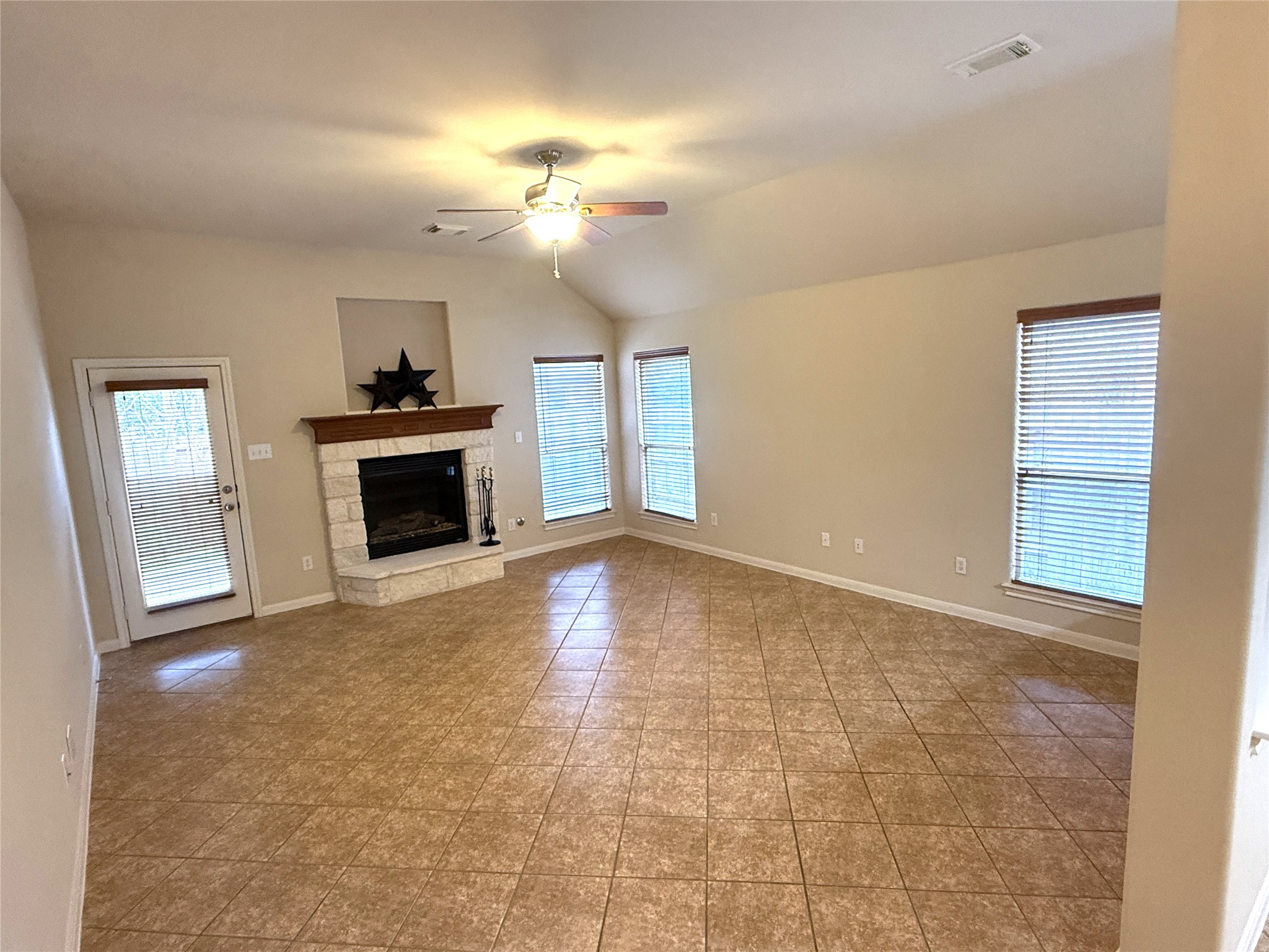 608 Pebblestone Walk Drive Cedar Park, TX 78613 - Photo 11 of 27 Unfurnished living room featuring a ceiling fan, a fireplace, vaulted ceiling, and light tile patterned flooring