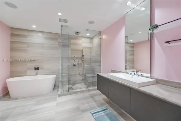 a bathroom with a tub sink mirror and shower