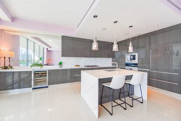 a large white kitchen with stainless steel appliances kitchen island granite countertop a stove a sink a table and chairs