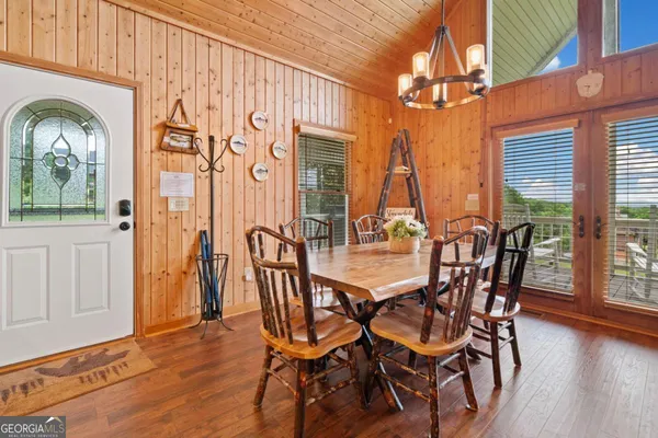 a kitchen with stainless steel appliances granite countertop a stove top oven a sink a dining table and chairs with wooden floor