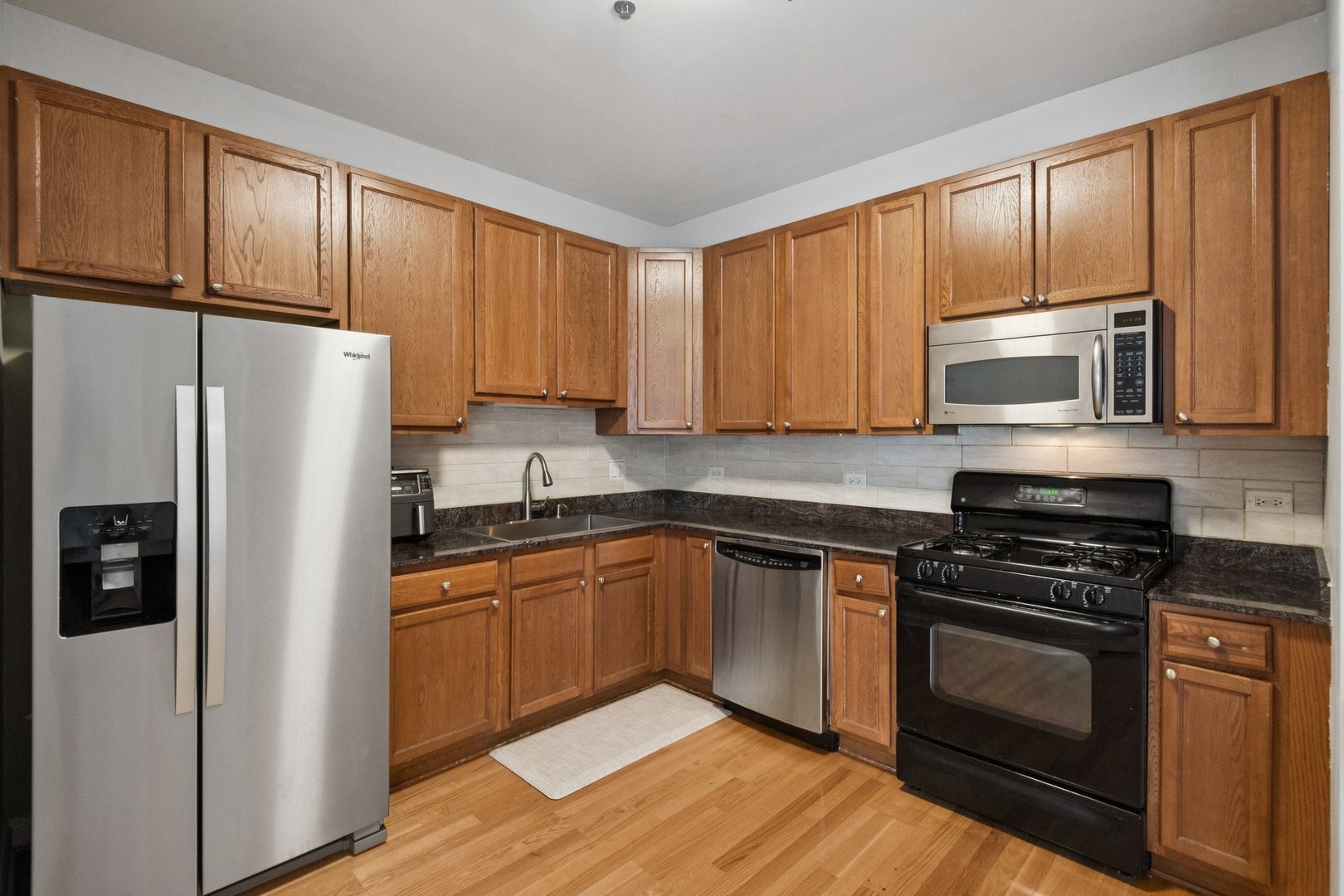 8 West Monroe Street, Unit 1209 Chicago, IL 60603 - Photo 8 of 24 a kitchen with granite countertop wooden cabinets a stove a sink and a refrigerator with wooden floor
