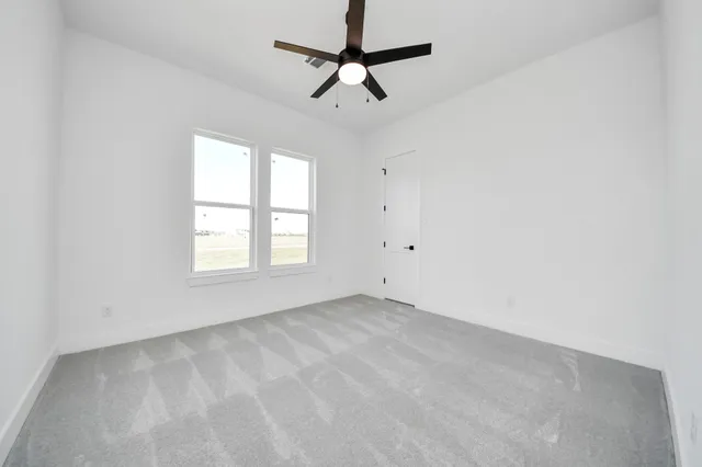 an empty room with a window and a fan