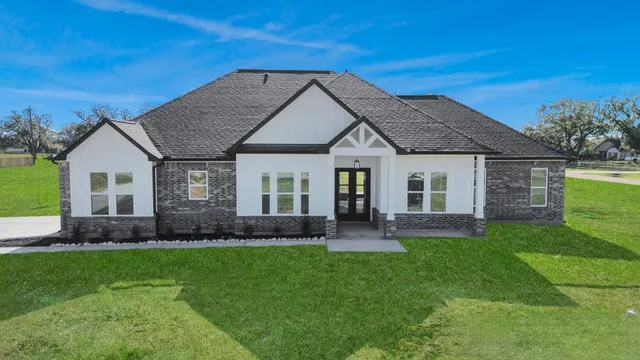 a front view of a house with a yard and trees