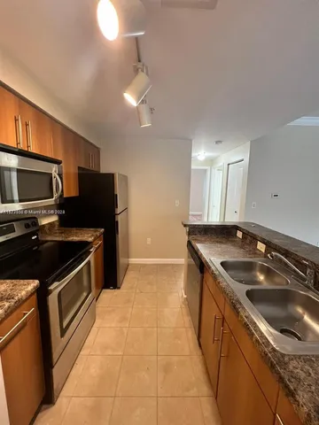 a kitchen with granite countertop a refrigerator and a stove top oven