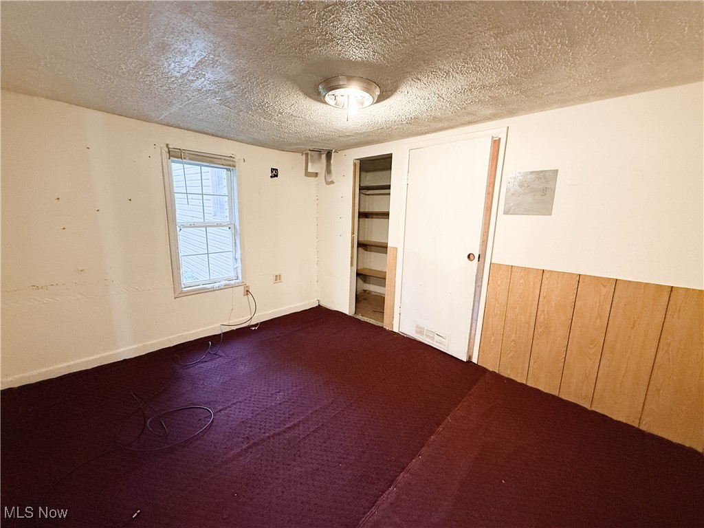 8756 Cook Road Salem, OH 44460 - Photo 26 of 50 Unfurnished bedroom with a textured ceiling, wood walls, and dark colored carpet