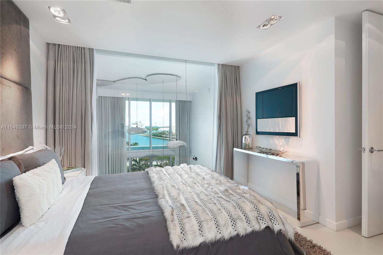 900 Biscayne Boulevard, Unit 705 Miami, FL 33132 - Photo 25 of 30 a bedroom with a bed and a flat screen tv