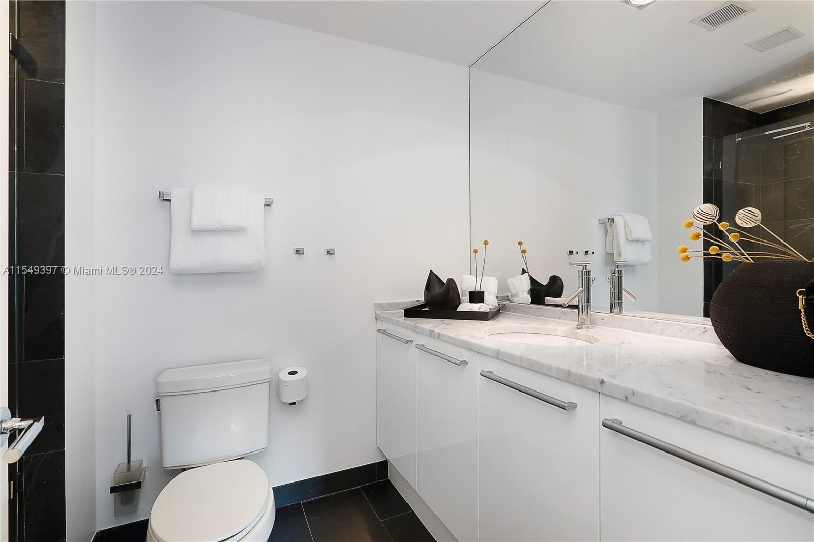 900 Biscayne Boulevard, Unit 705 Miami, FL 33132 - Photo 26 of 30 a bathroom with a granite countertop toilet sink and mirror