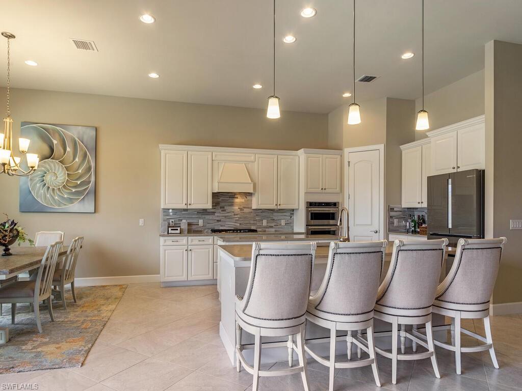 7263 Clamshell Lane Naples, FL 34114 - Photo 5 of 11 a kitchen with stainless steel appliances kitchen island granite countertop a dining table chairs and a refrigerator
