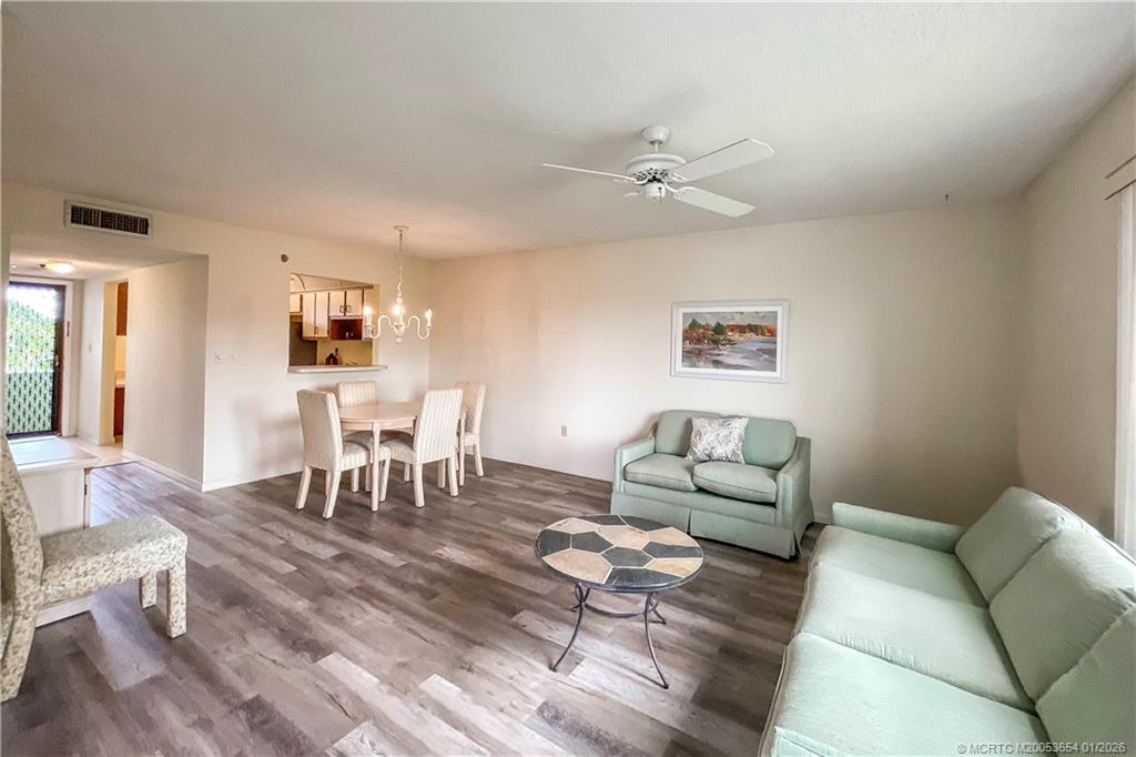 5403 Southeast Miles Grant Road, Unit 209 Stuart, FL 34997 - Photo 5 of 18 a living room with furniture and a dining table with wooden floor