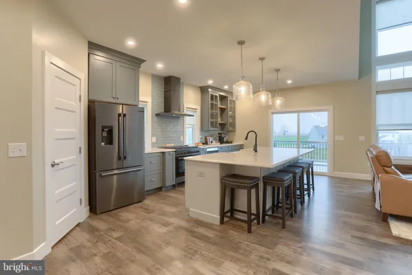 a kitchen with stainless steel appliances granite countertop a refrigerator a stove a sink a dining table and chairs with wooden floor