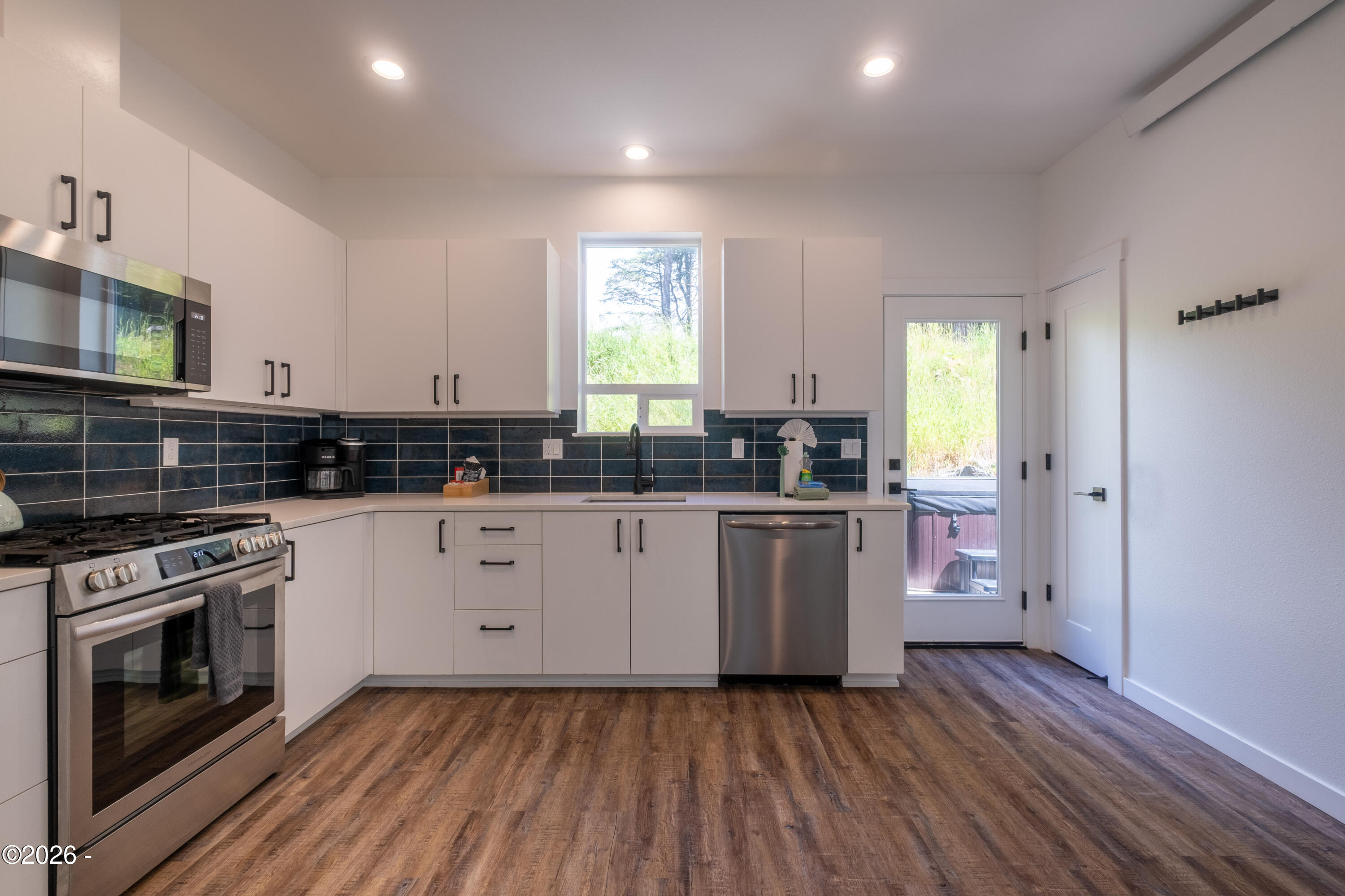 500 Southeast Shell Avenue Depoe Bay, OR 97341 - Photo 22 of 33 SS appliances, white quartz counter are offset by darker subway tile backsplash and under counter lighting. Door out to the patio with the pantry to the right of the back door.