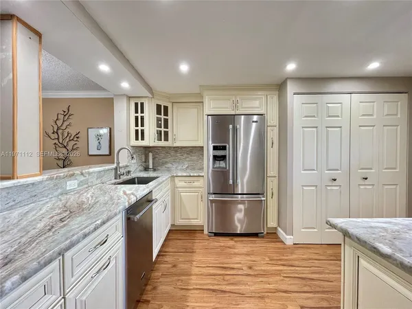 a kitchen with stainless steel appliances granite countertop a refrigerator and a sink
