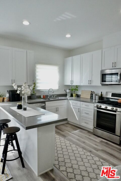 1157 South Point View Street Los Angeles, CA 90035 - Photo 3 of 15 a kitchen with stainless steel appliances granite countertop a sink a stove top oven a counter space and cabinets