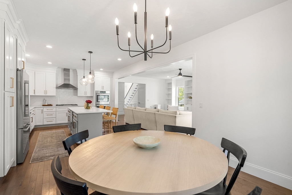 32 Cutter Lane, Unit 32 Amesbury, MA 01913 - Photo 13 of 37 a kitchen with stainless steel appliances kitchen island granite countertop a stove a sink a dining table and chairs with wooden floor