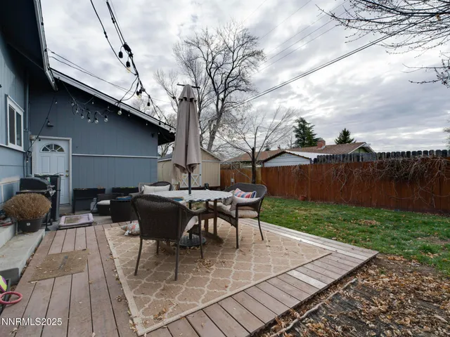 a view of backyard with table and chairs couches with wooden fence and plants