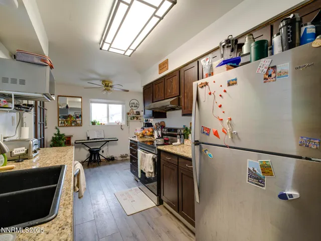 a kitchen with granite countertop a refrigerator a sink dishwasher a stove and a dining table with wooden floor