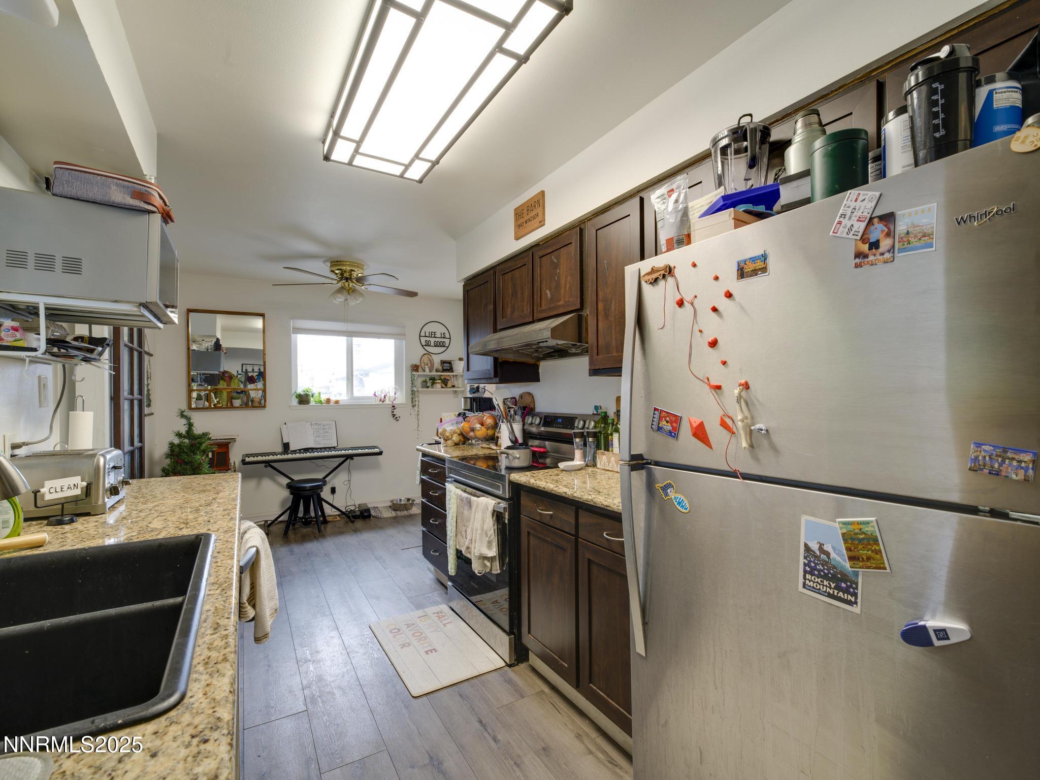 1840 Windsor Way Reno, NV 89503 - Photo 8 of 21 a kitchen with granite countertop a refrigerator a sink dishwasher a stove and a dining table with wooden floor