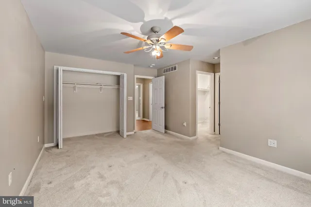 an empty room with closet and a ceiling fan